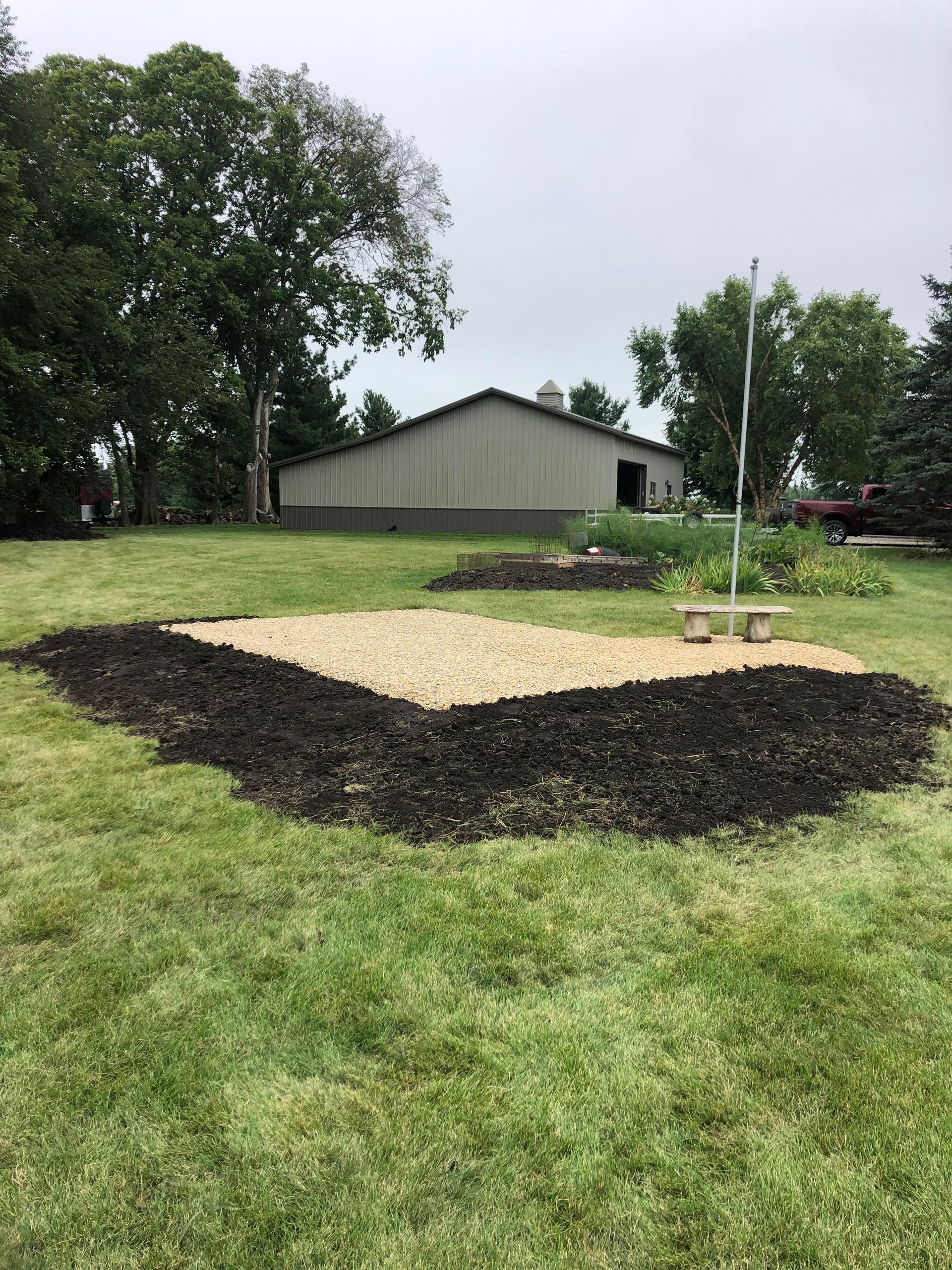 A large pile of dirt is in the middle of a lush green field.