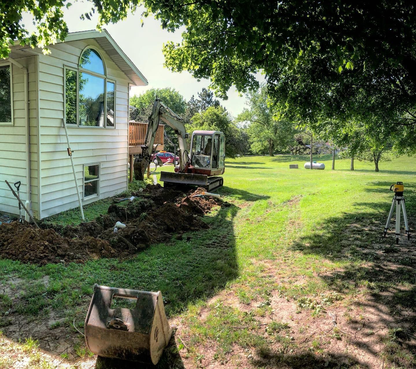 An excavator is digging a hole in front of a house