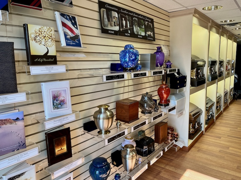 Wall display in a funeral home showcasing urns, memorial books, and keepsakes.