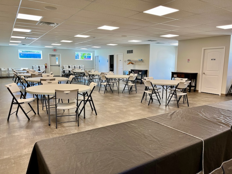 Empty event room with round tables and chairs. Black tablecloth in the foreground.