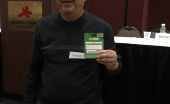 Person holding Subway gift card, smiling in front of a conference table.