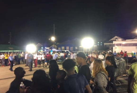 Crowd of people at a nighttime event under bright lights.