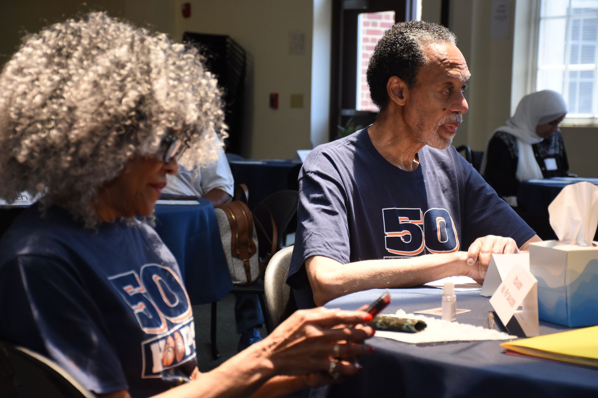People at a table, some wearing matching blue shirts with 