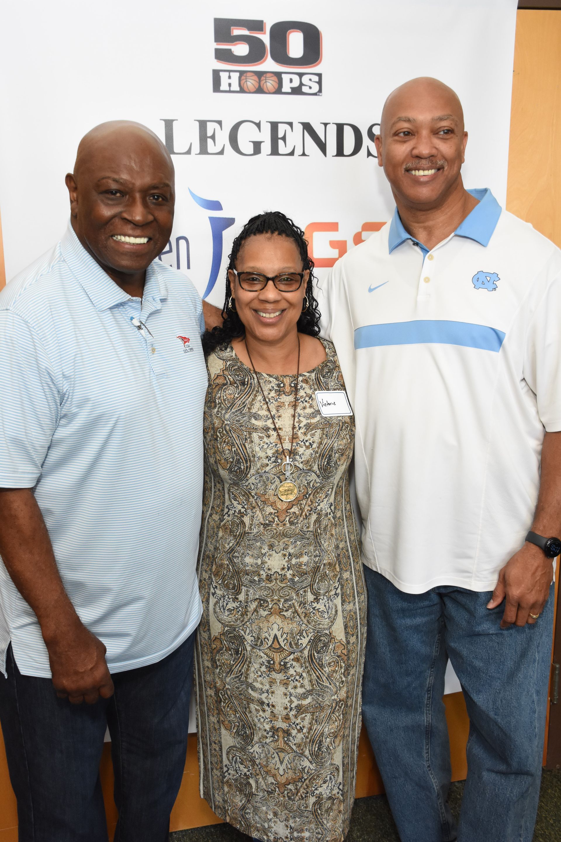 Three people smiling in front of a 