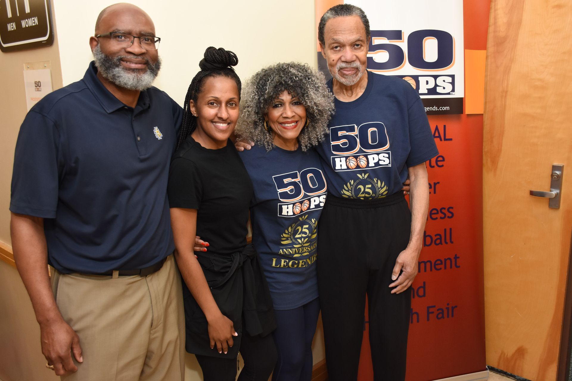 Four people smiling, posing near a 
