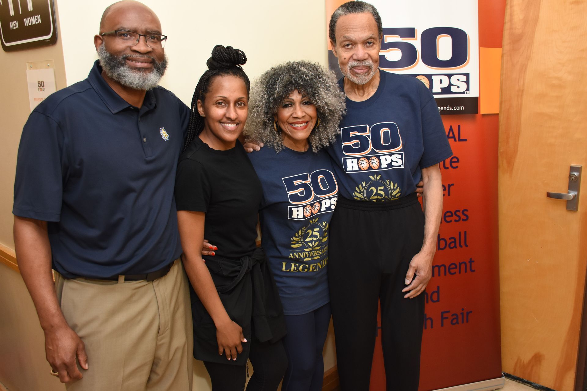 Four people standing together. Two are wearing 
