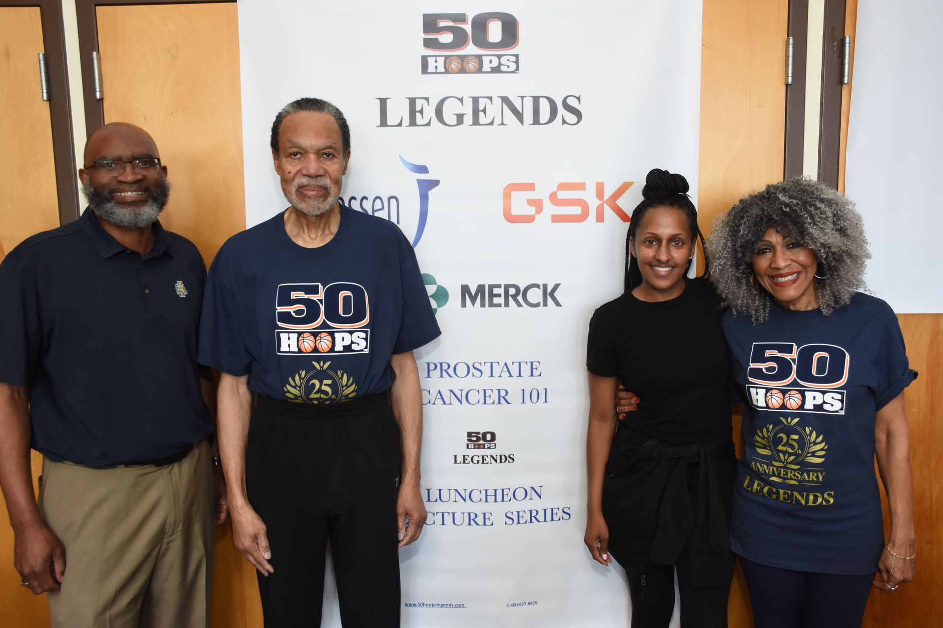Four people stand in front of a banner w