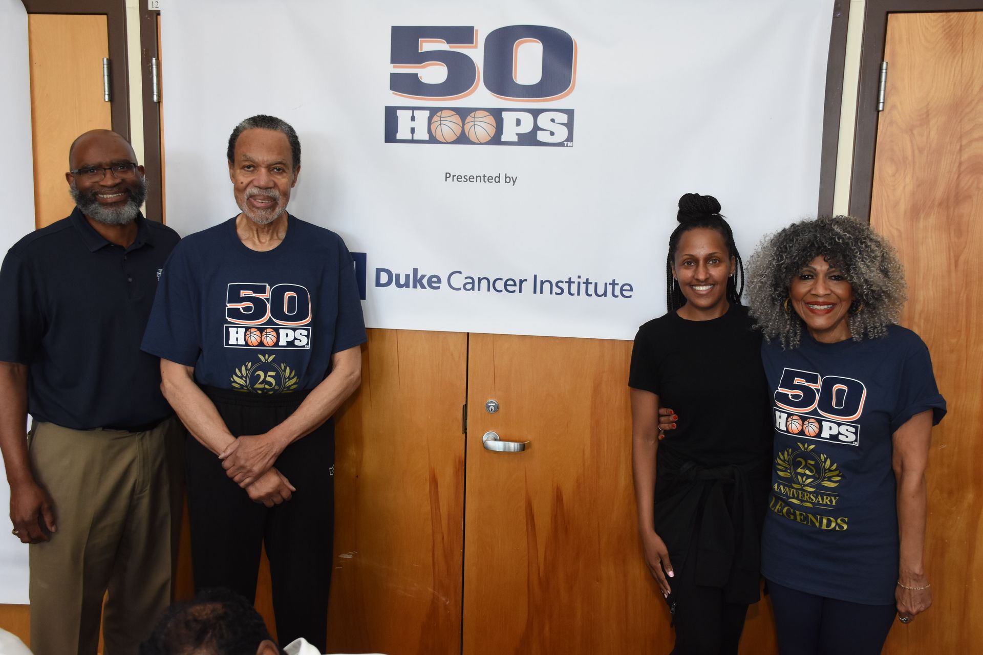 Four people stand in front of a banner for 