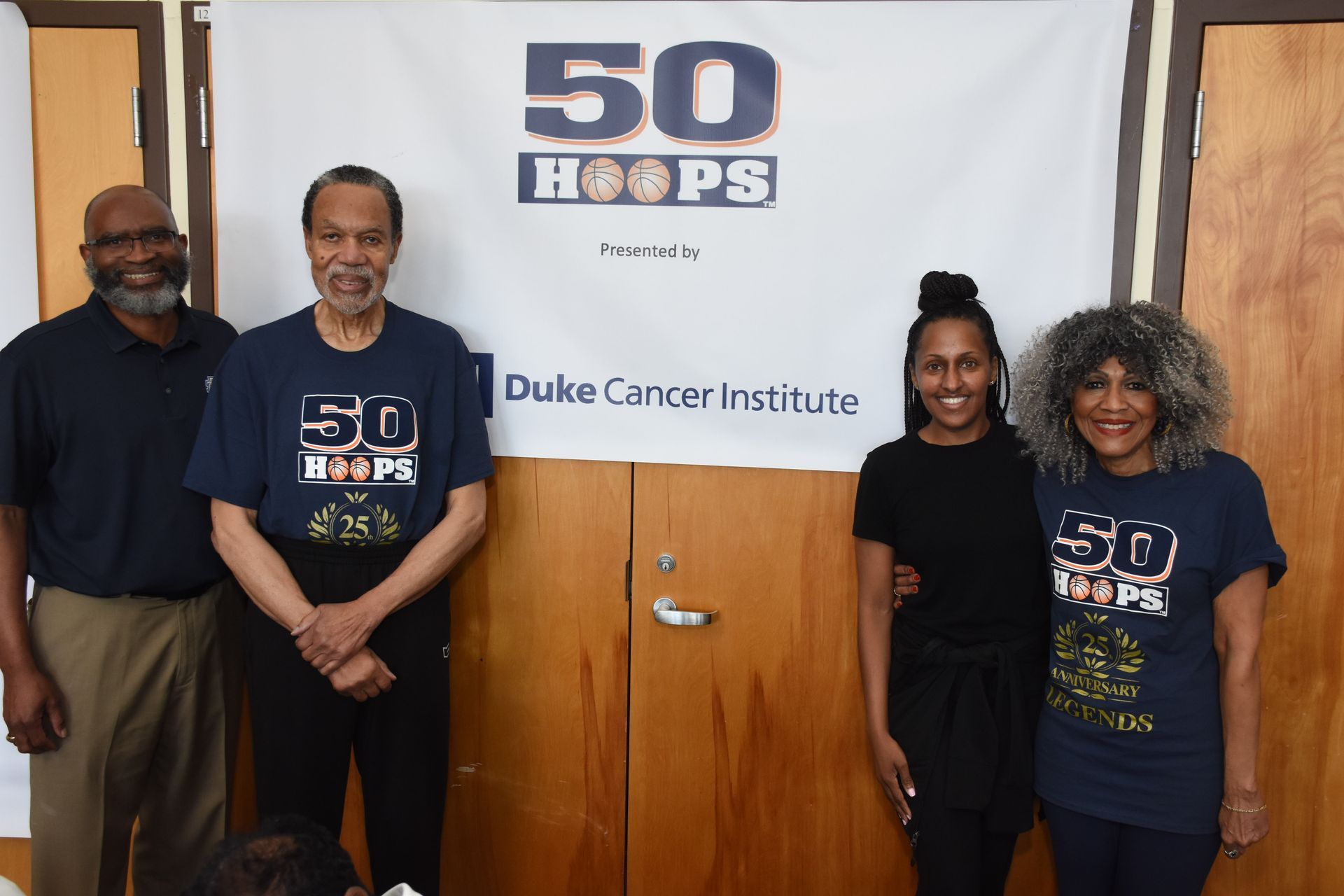 Four people pose in front of a banner for 