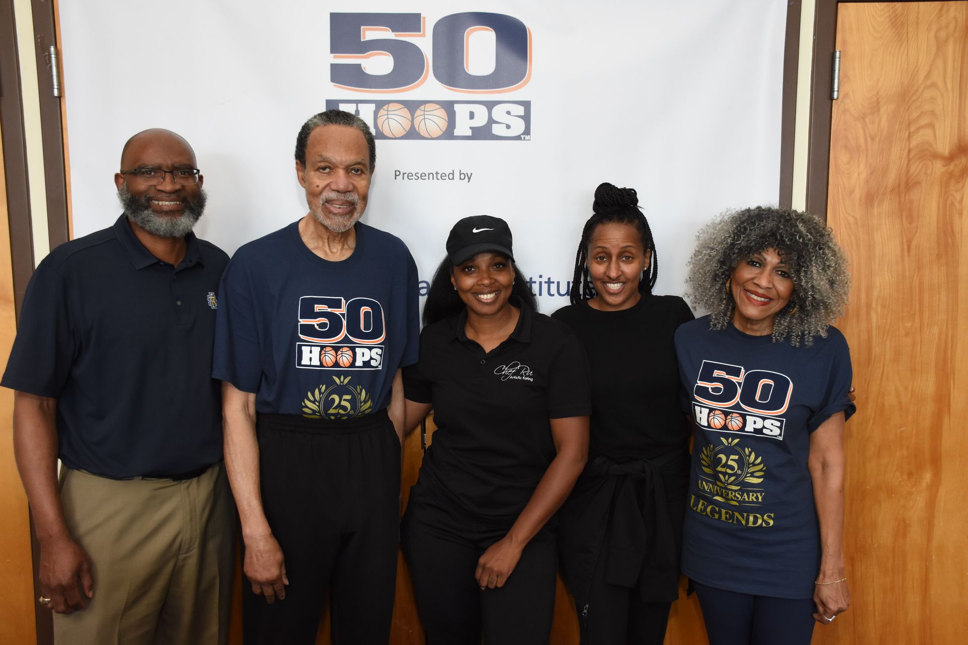 Five people posing in front of a banner that says 
