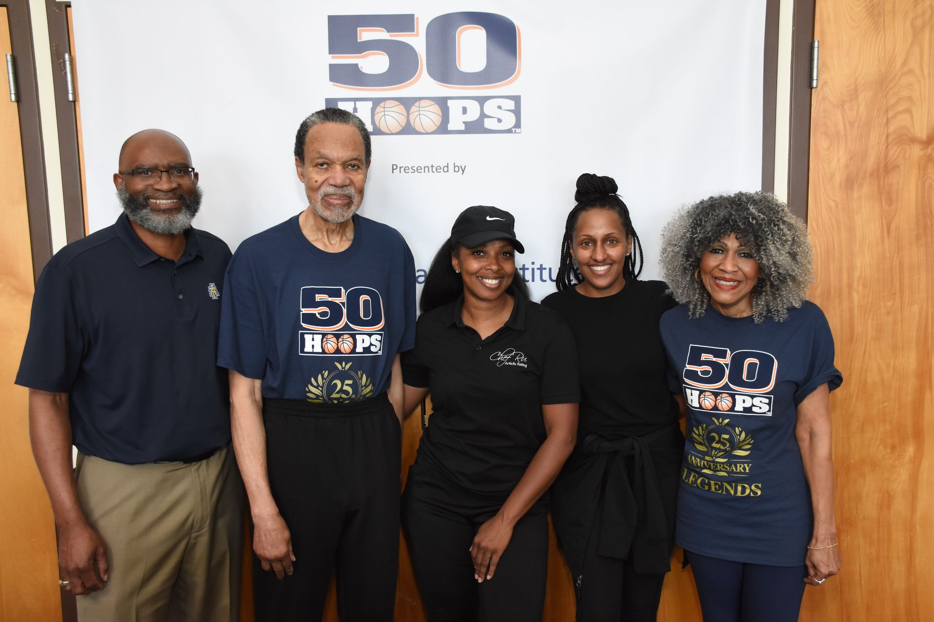 Group of five people posing in front of a banner that reads 
