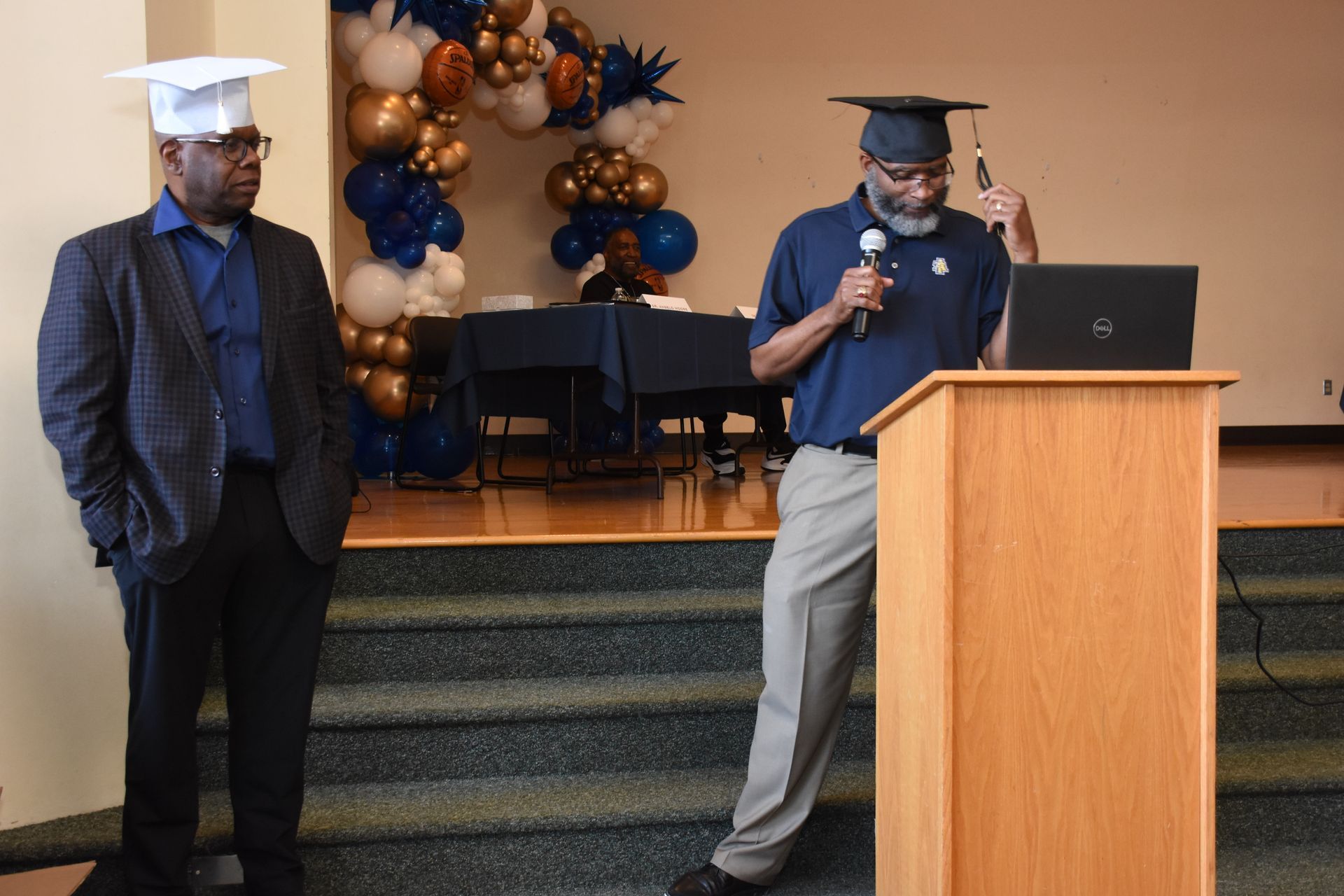 Two men in graduation caps at a podium