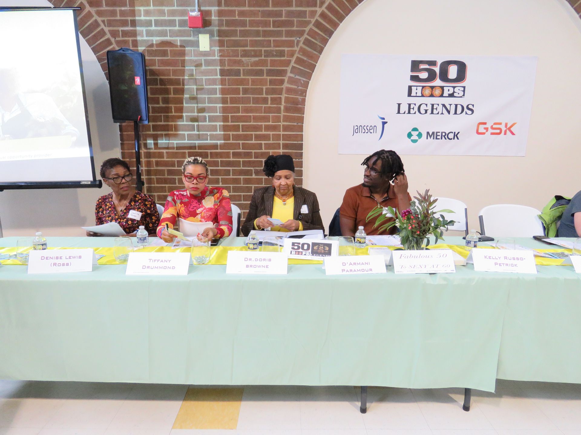 Panel of four women at a table, discussing topics.  Banner reads 