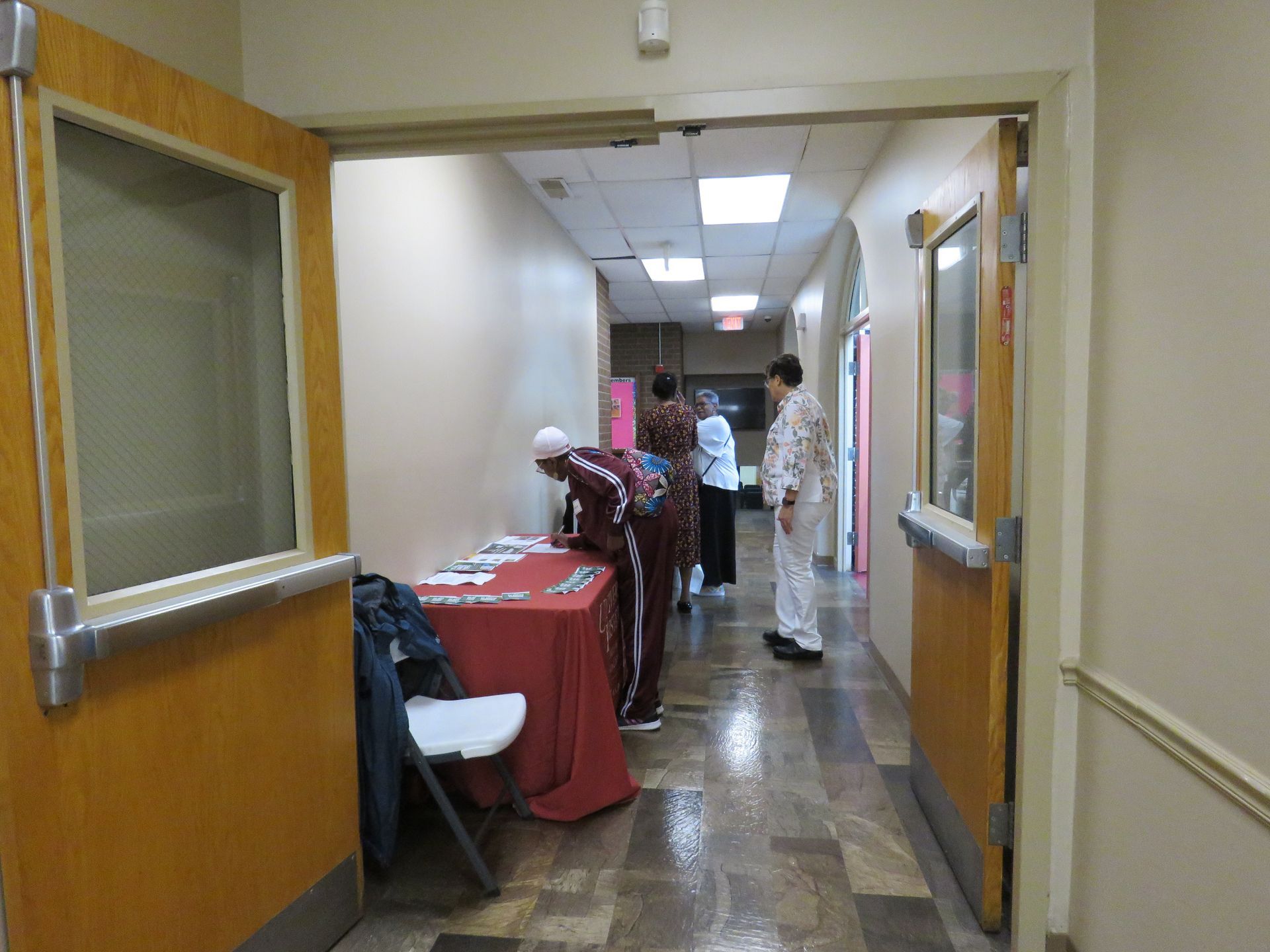Hallway with people near a table; one person is signing a paper.
