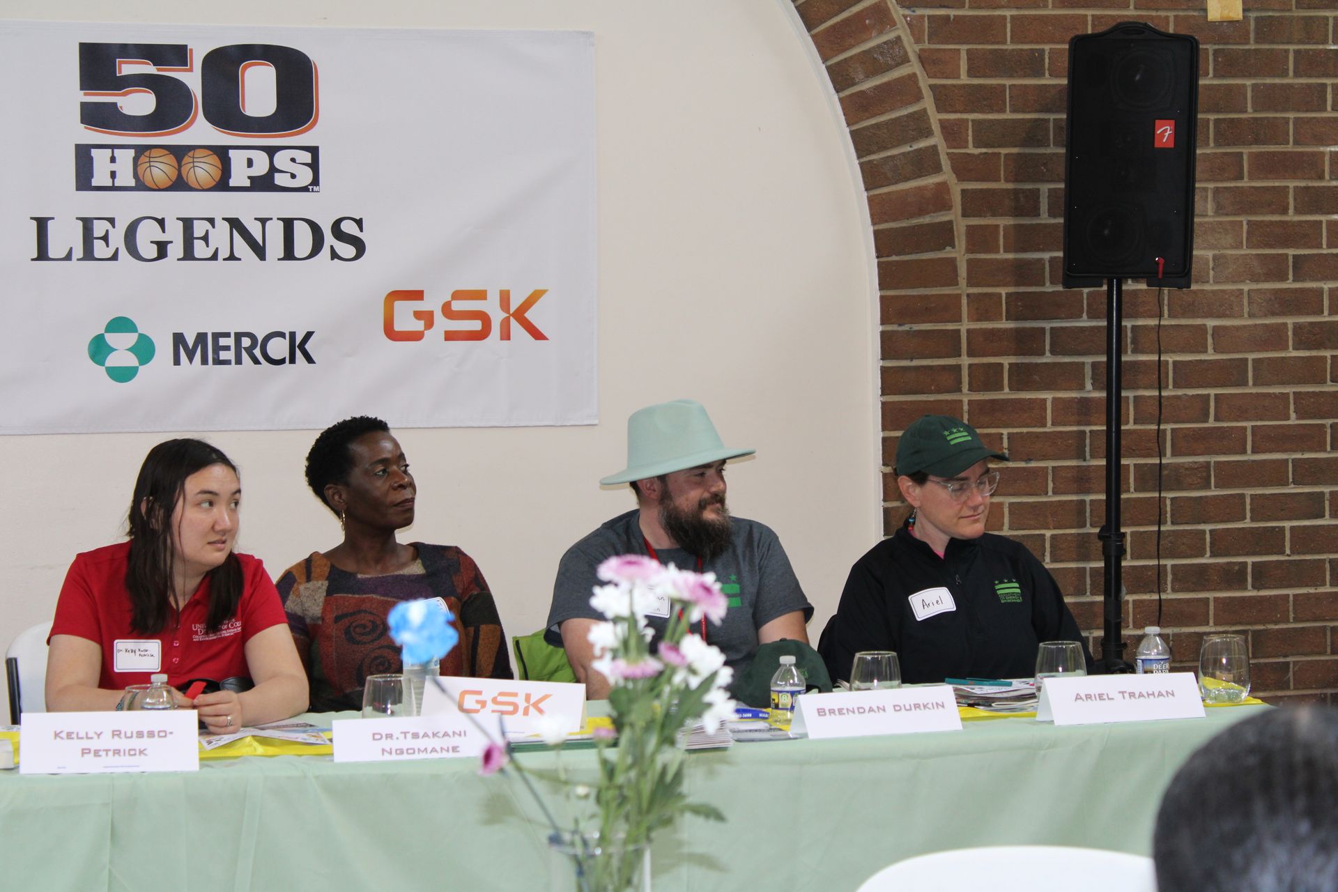 Panel discussion with four people seated at a table, with a banner that reads 