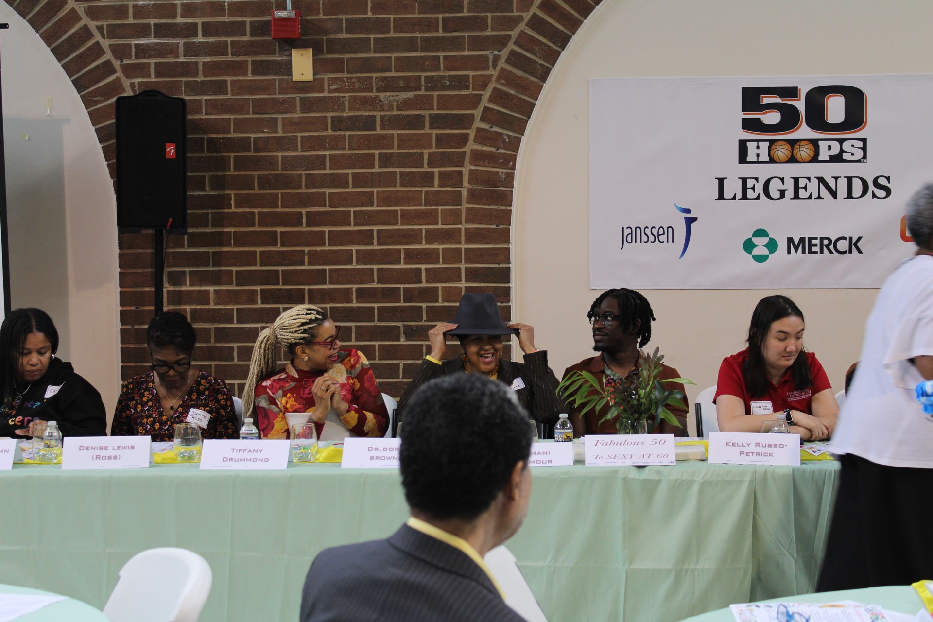 Panel of speakers at a conference, sitting behind a table with a 