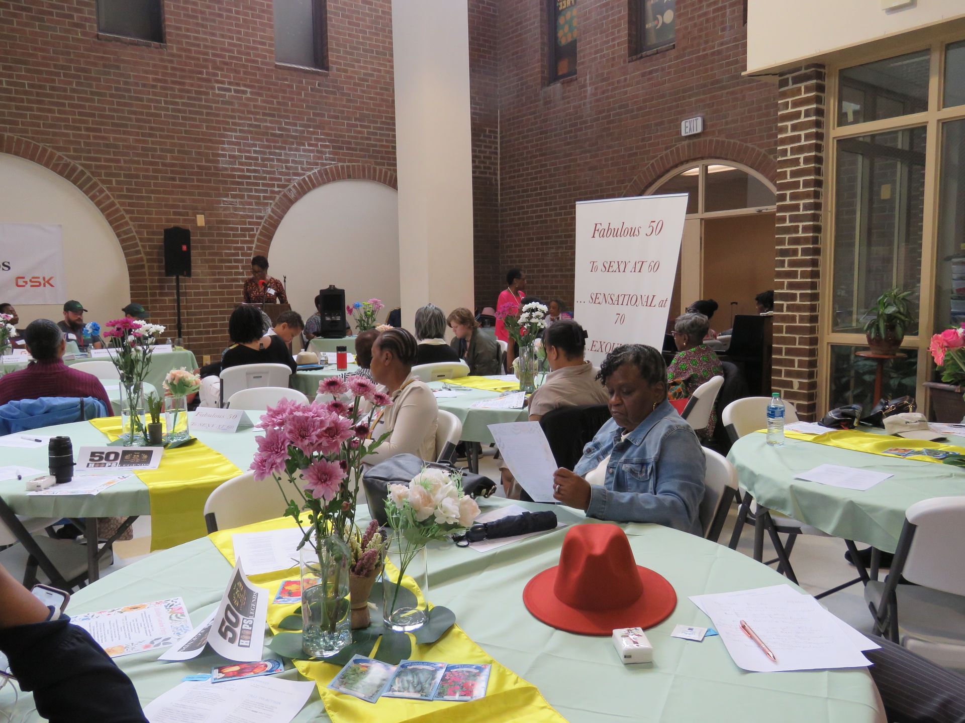 People seated at round tables in a brick-walled room.