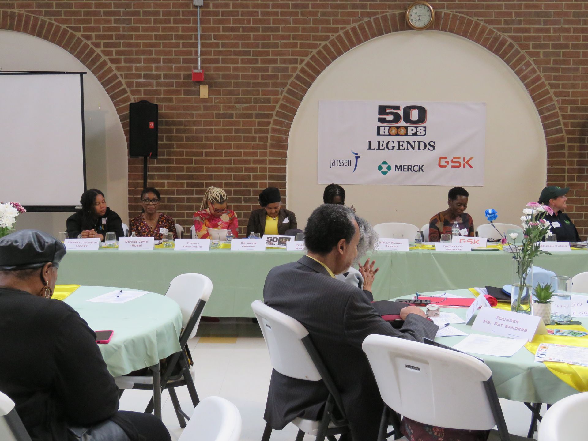 Panel discussion with speakers at a table, banner reads 