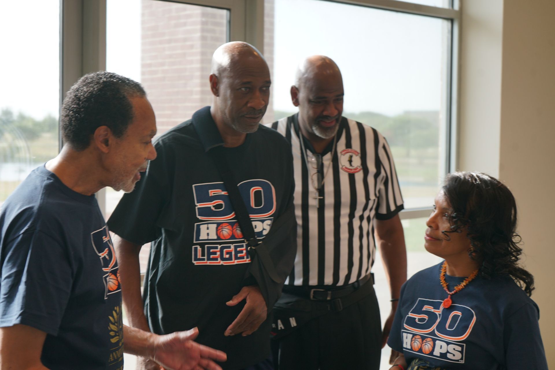 Four people in matching shirts talking, two men wearing referee attire.