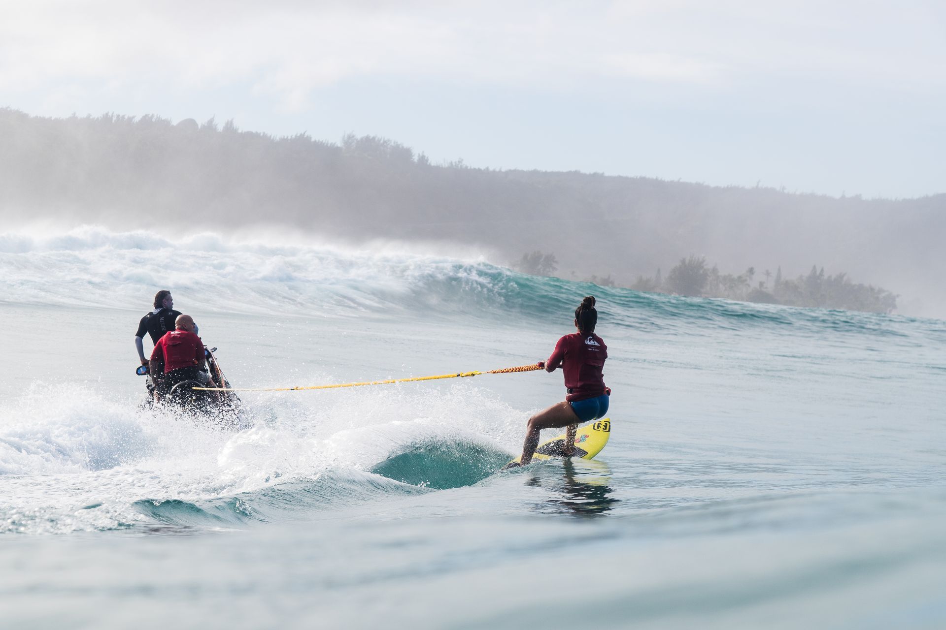 Two people on a red, yellow, and blue jet ski riding on calm water