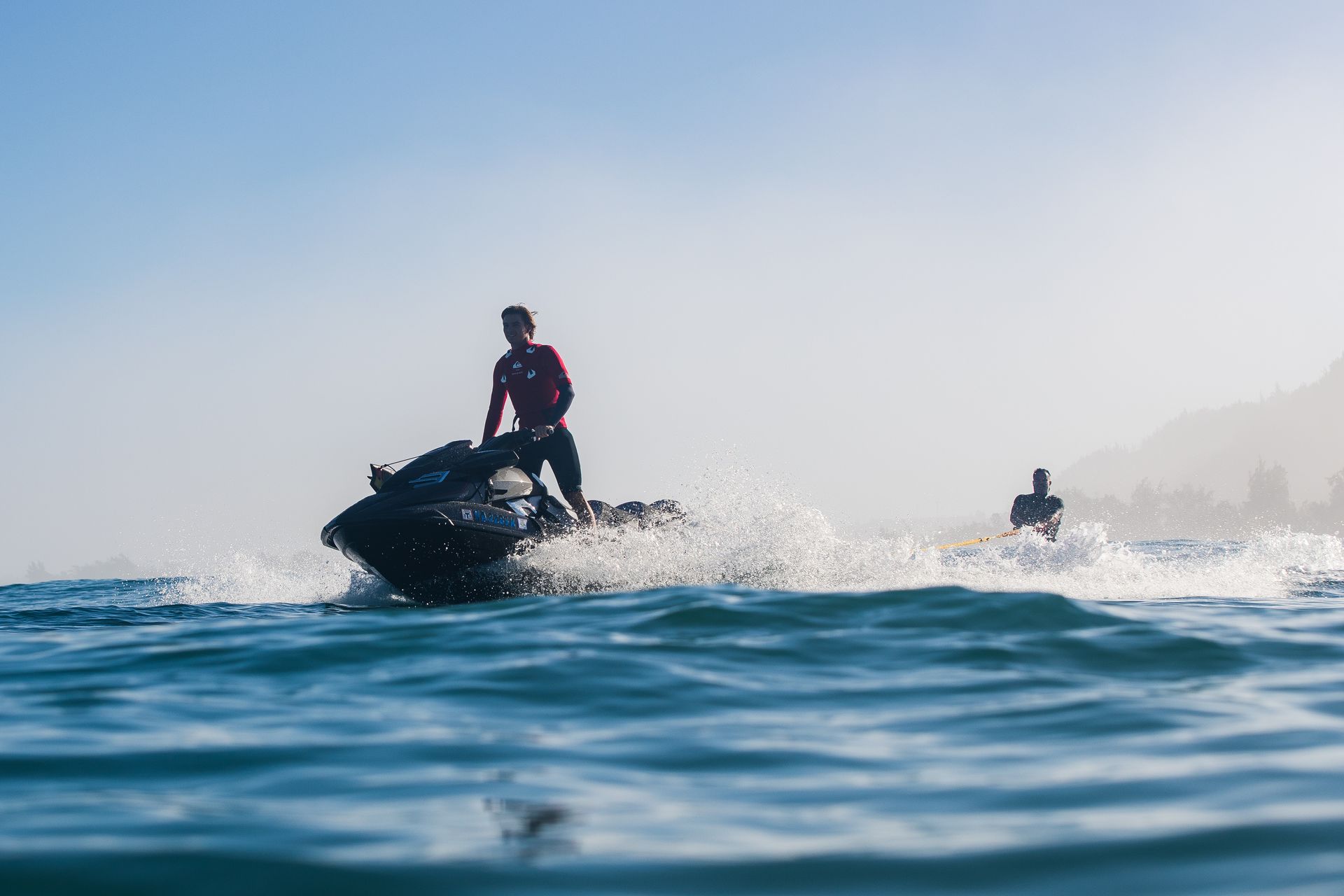 Two people on a red-and-blue jet ski riding on open water