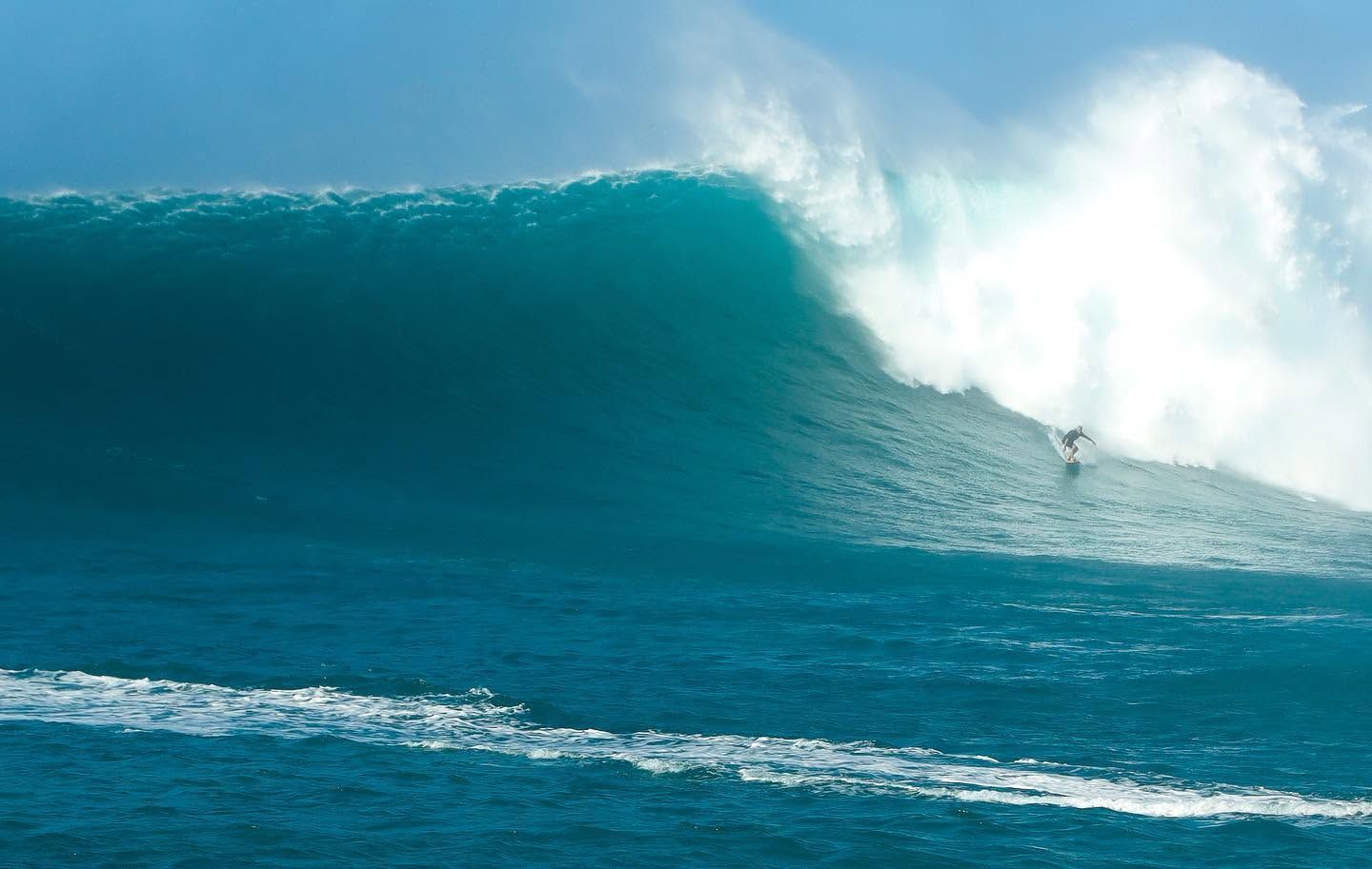 A large turquoise ocean wave curling with white spray over the sea