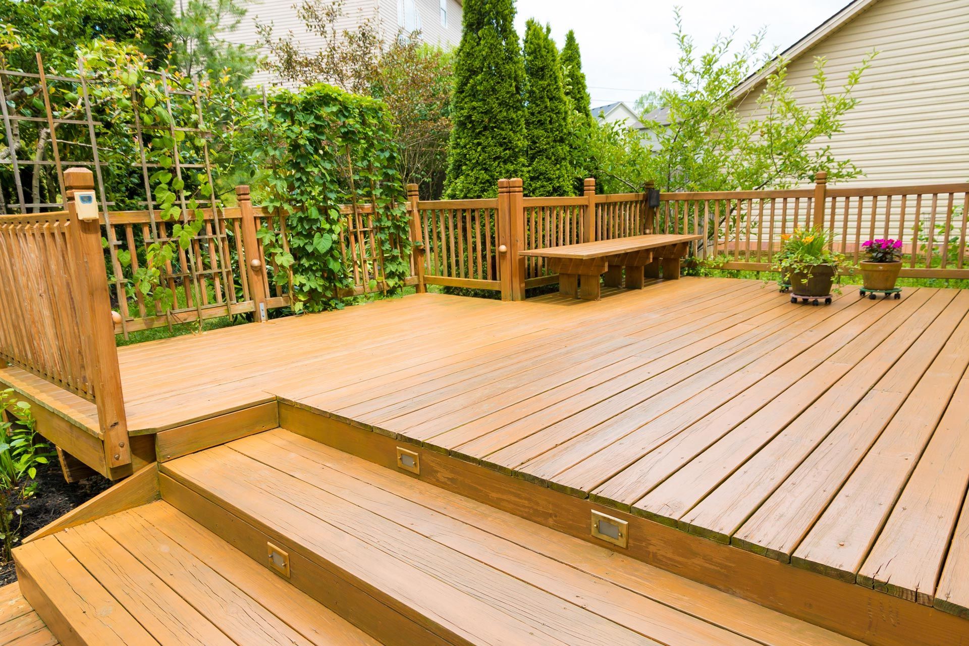 A wooden deck with stairs and a bench in the backyard of a house