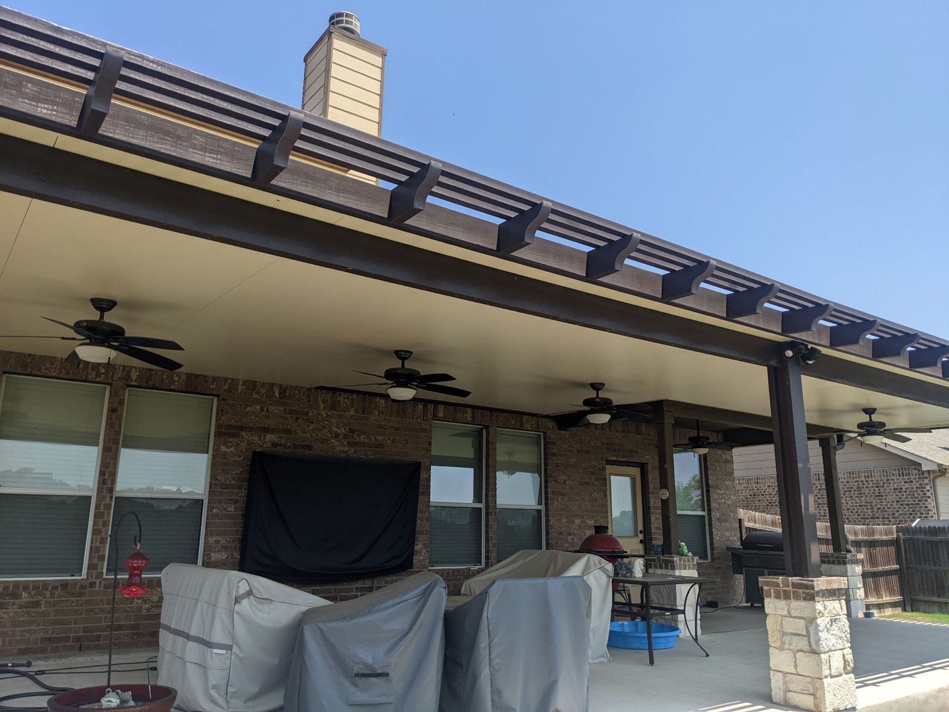 A brick house with a covered porch and a ceiling fan.
