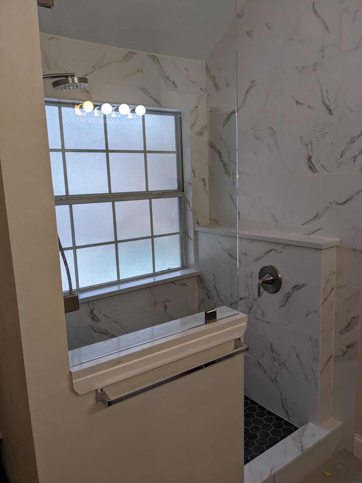 A bathroom with a walk in shower and a window.