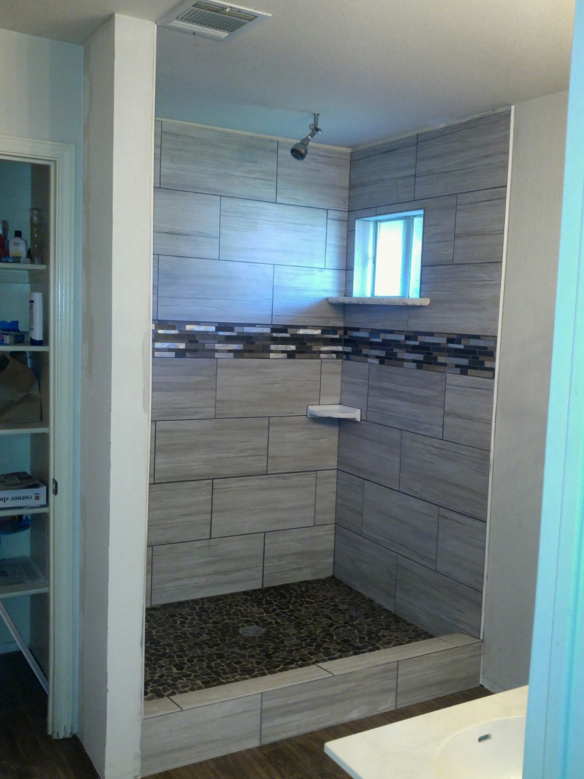 A bathroom with a walk in shower and a window.