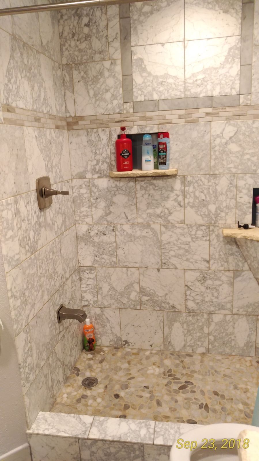 A bathroom with marble tiles and a walk in shower.