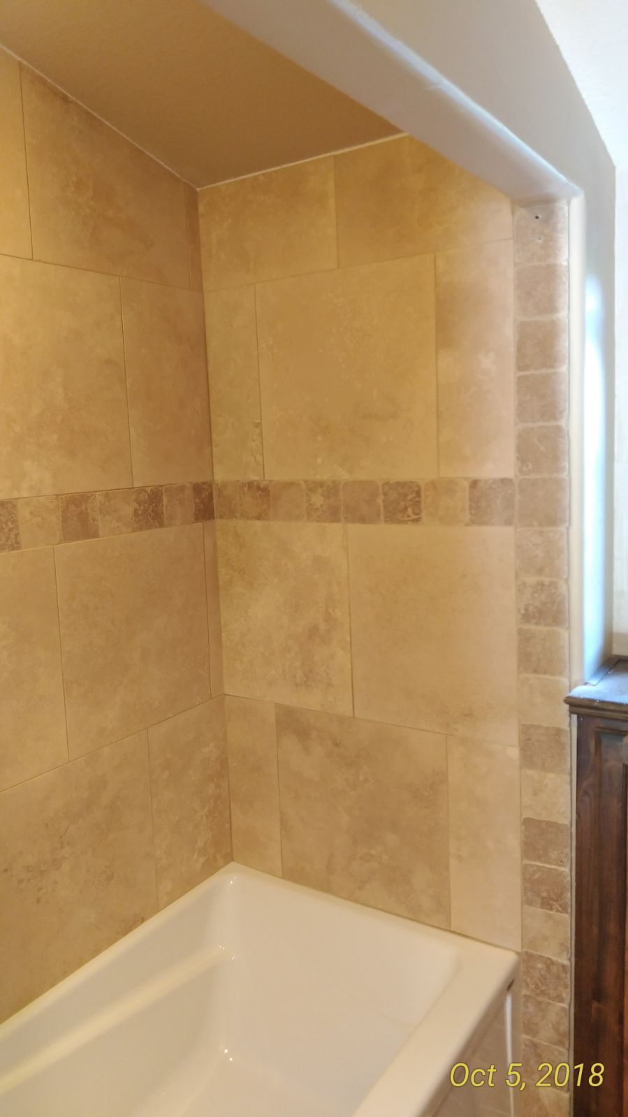 A bathroom with a bathtub and tiled walls.
