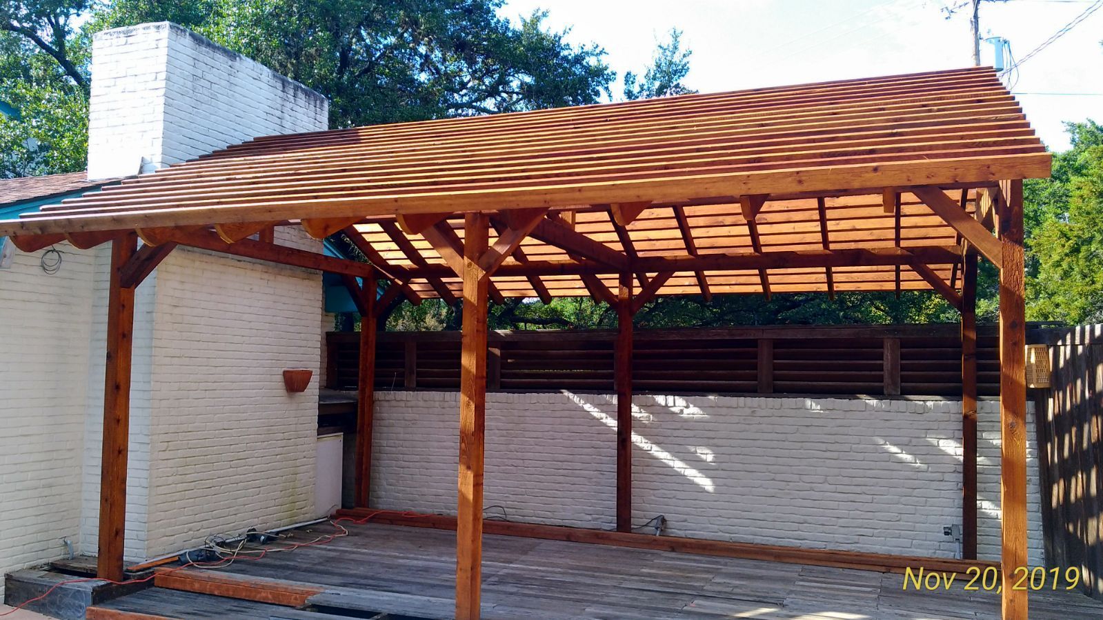 A wooden pergola is being built on the side of a house