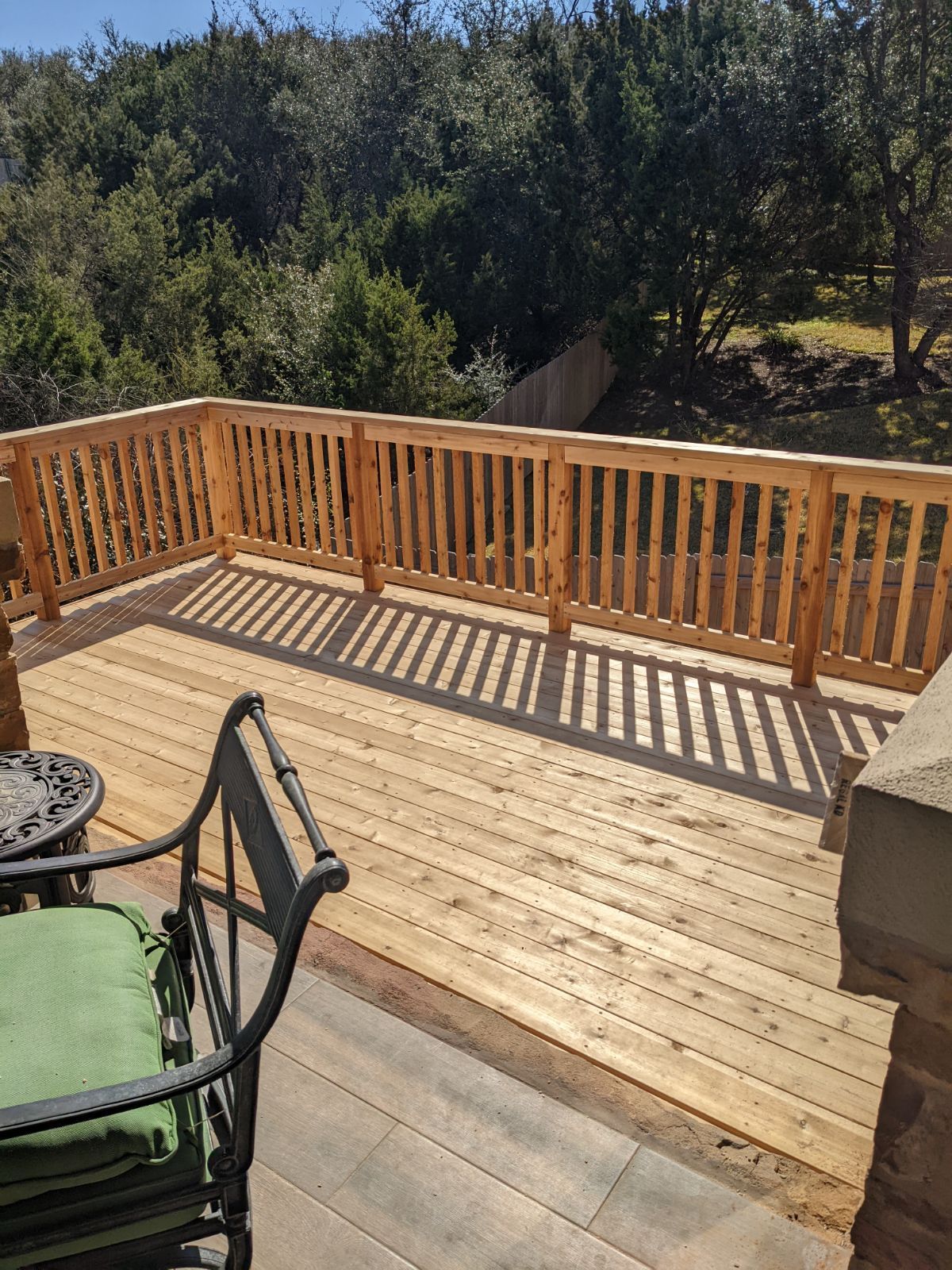 A wooden deck with a table and chairs and trees in the background.