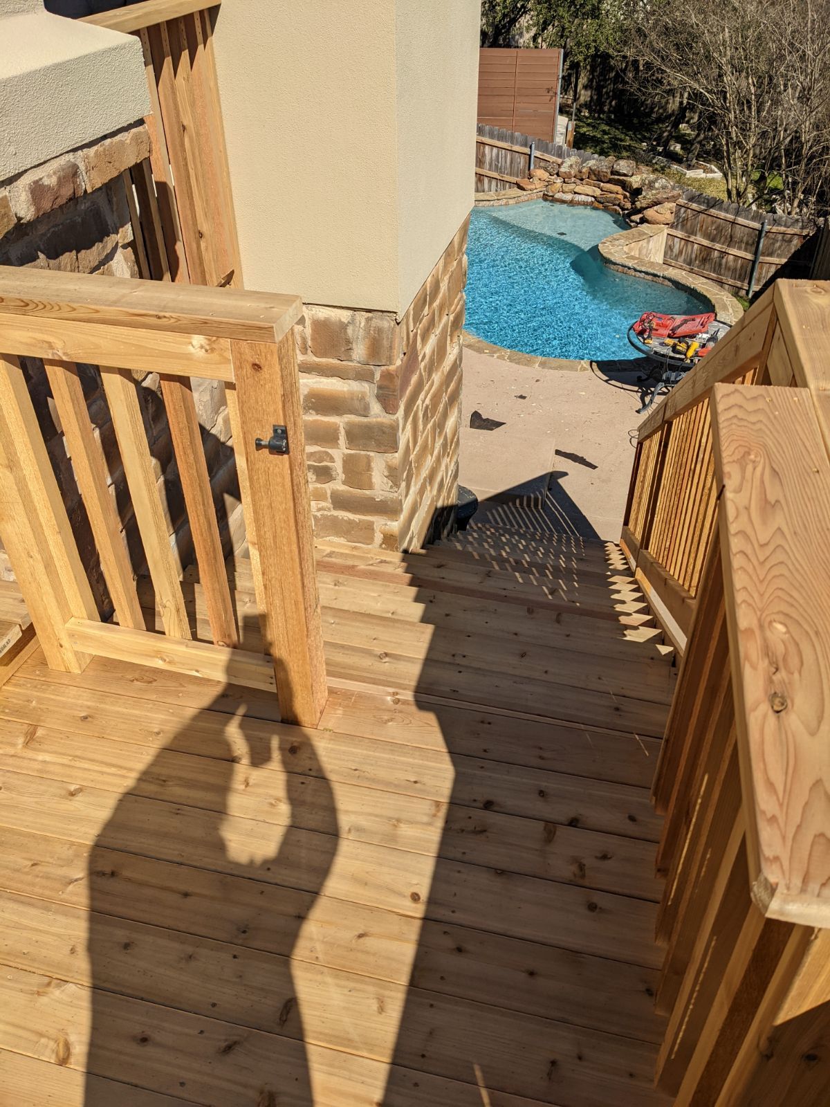 A wooden deck with stairs leading up to a pool.