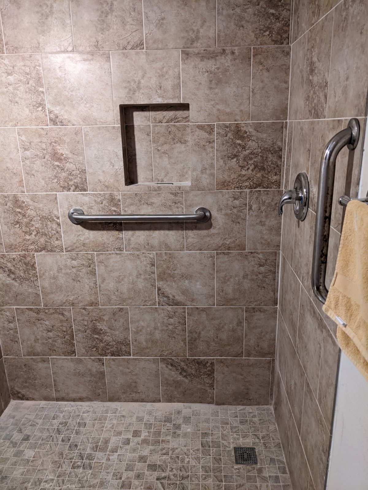 A bathroom with a walk in shower and a towel rack.