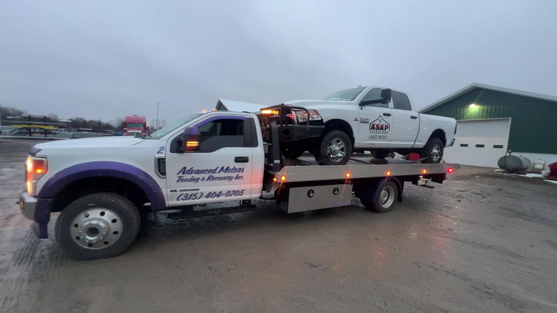 A white truck is being towed by a tow truck.