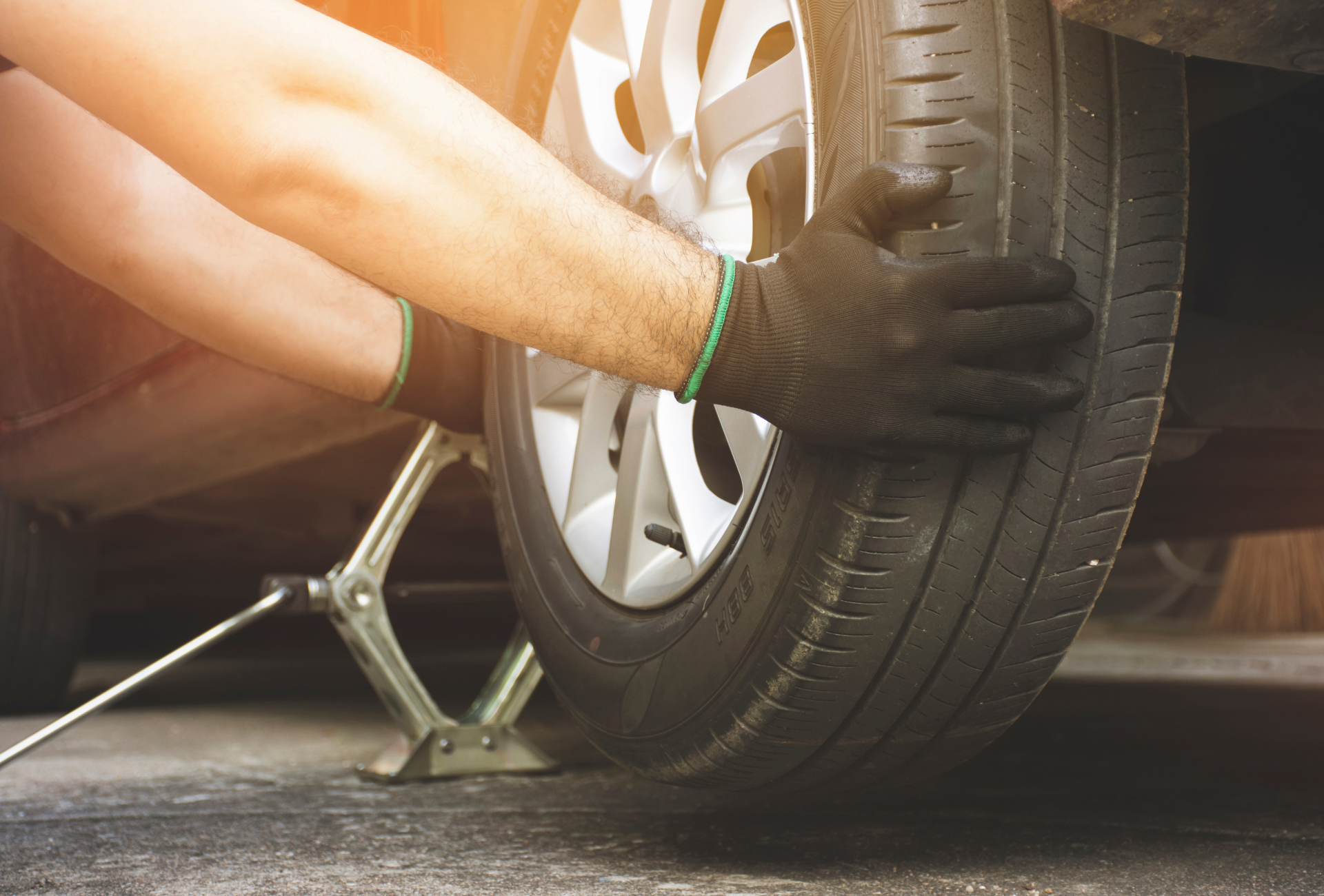 A man is changing a tire on a car with a jack.