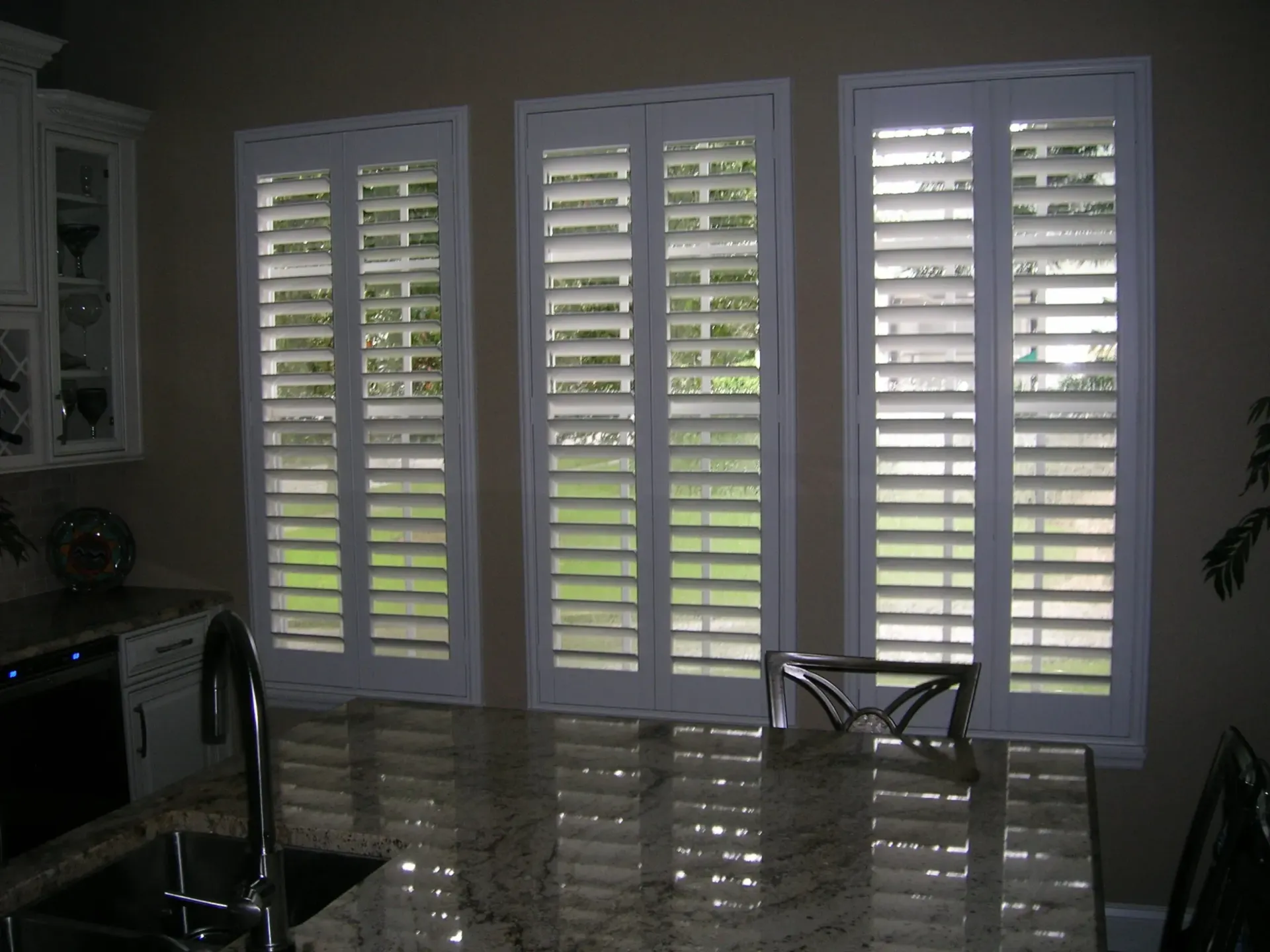 Living room with white plantation shutters, glossy tile floor, and furniture in dim light