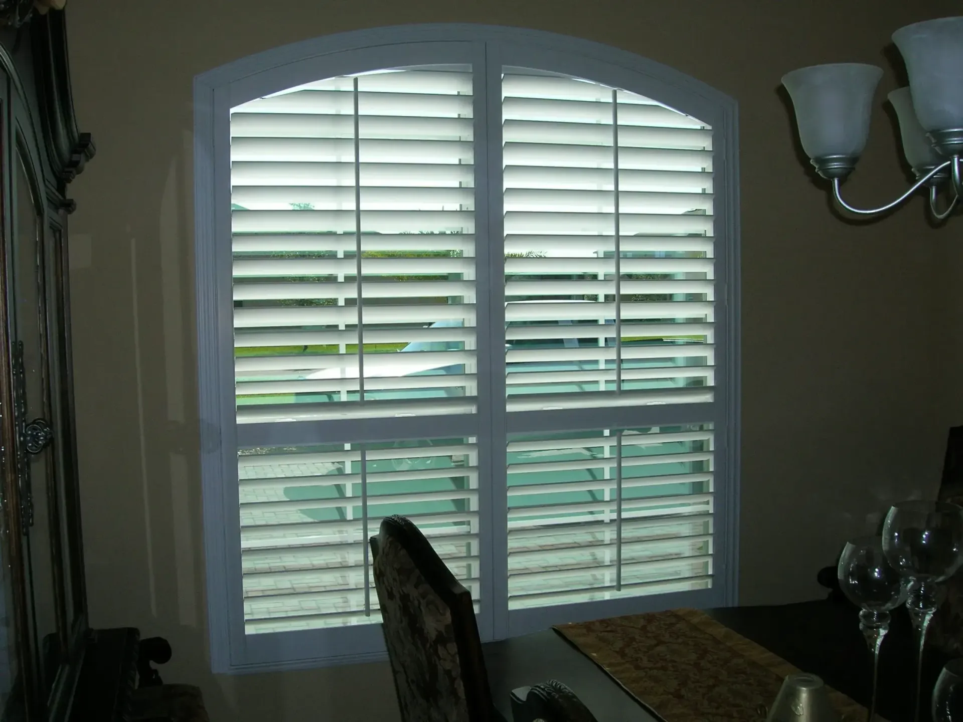 Shuttered window with a chair silhouetted in a dim room