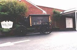Small red brick building with a wagon wheel display and a sign outside on a street corner