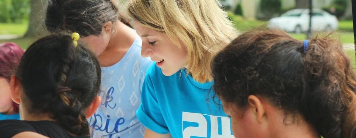 A woman in a blue shirt is talking to a group of children. A woman in a blue shirt is talking to a group of children.