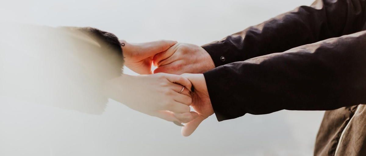 A close up of a person holding another person 's hand. A close up of a person holding another person 's hand.