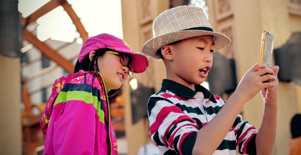 A boy and a girl are looking at a cell phone. A boy and a girl are looking at a cell phone.