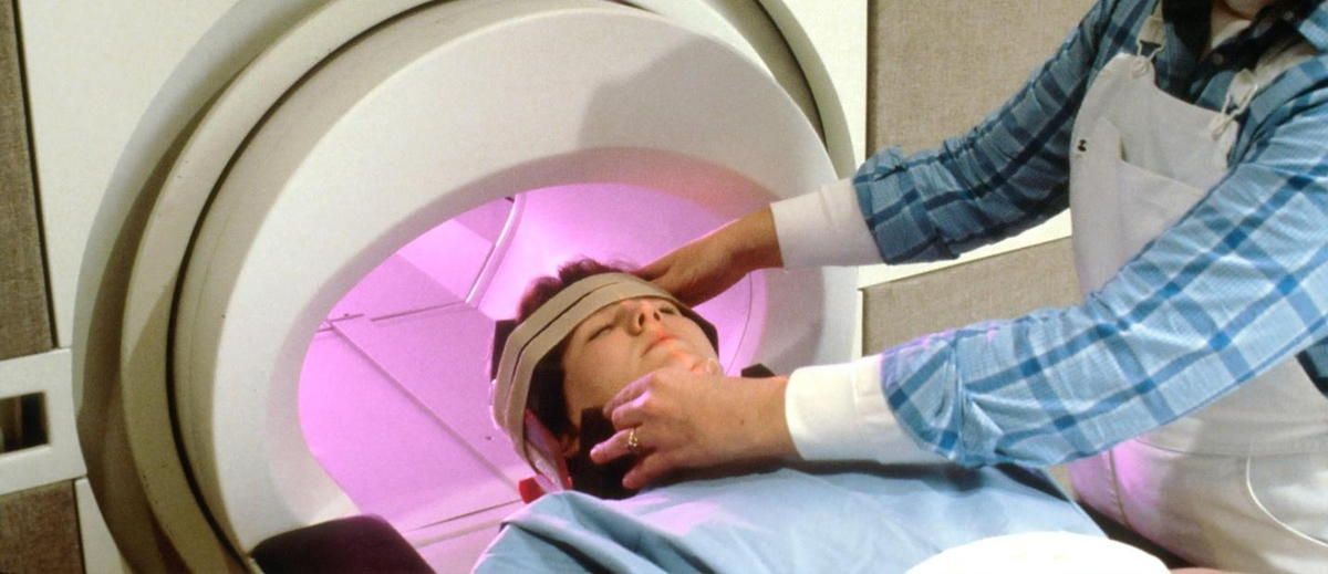 A person is laying in a machine with a bandage on their head. A person is laying in a machine with a bandage on their head.