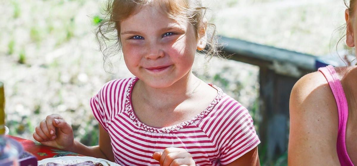 A little girl is sitting at a table eating a piece of cake. A little girl is sitting at a table eating a piece of cake.