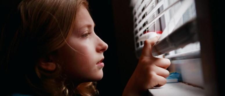 A young girl is looking out of a window. A young girl is looking out of a window.
