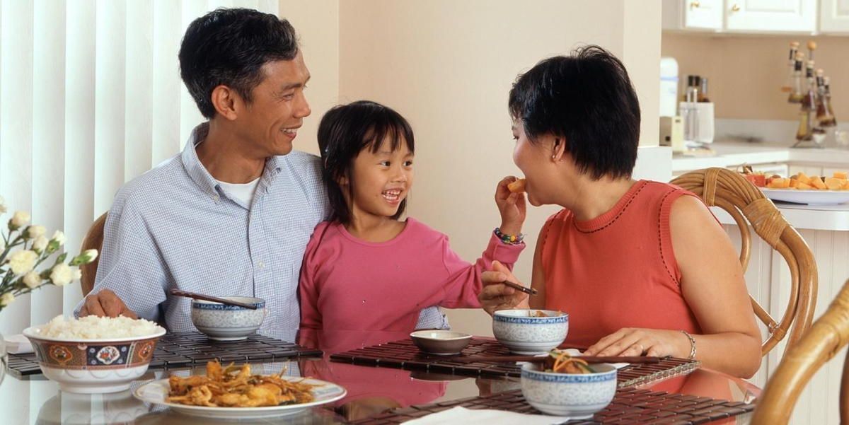 A family is sitting at a table eating food. A family is sitting at a table eating food.