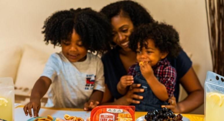A woman and two children are sitting at a table eating food. A woman and two children are sitting at a table eating food.