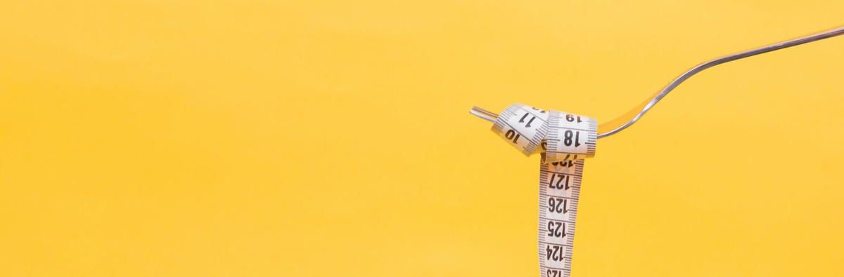 A measuring tape is tied to a fork on a yellow background. A measuring tape is tied to a fork on a yellow background.